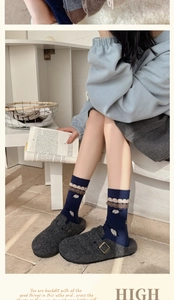 Detail of navy blue wool socks with wave patterns and grey felt slippers on a model