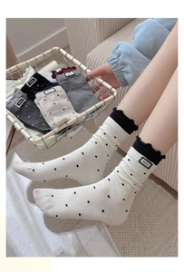 Detail of cotton crew socks with polka dots, ruffled cuffs, and M.E.K. fabric labels