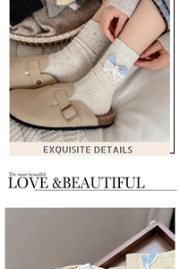 Close-up of off-white mid-tube socks with blue bow detailing and khaki buckled clogs