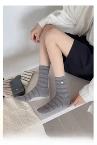 Close-up of striped cotton mid-calf socks featuring a metallic buckle detail on rib knit fabric