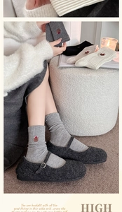 Detail of light grey wool socks with bear embroidery paired with Mary Jane shoes