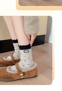 Detail of polka dot socks with ruffled edges and brand label worn with Mary Jane shoes