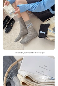 Close-up of ribbed cotton mid-calf socks with cute bow details and speckled yarn texture