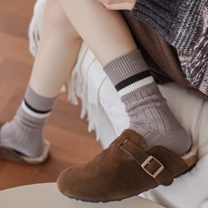 Mules en daim marron avec chaussettes en laine chaudes sur fond de parquet cosy