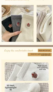 Detail of three wool socks in black, grey, and cream with cute bear embroidery