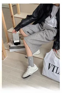 Détail de chaussettes en coton rayé gris avec une délicate broderie de points blancs