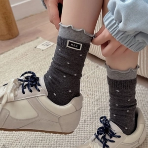 Polka dot crew socks with ruffle trim and MEK label worn with white sneakers