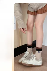 Nahaufnahme cremefarbener Strick-Wadenstrümpfe mit Retro-Schnür-Sportschuhen