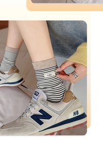 Close-up of striped cotton crew socks featuring a decorative beige egg fabric label