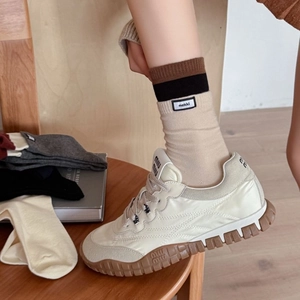 Cremefarbene Plateau-Sneaker mit Gummisohle und gerippten Socken in gemütlichem Ambiente