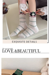 Detail of cream cotton socks with green stripes, pink ruffle trim and bear embroidery