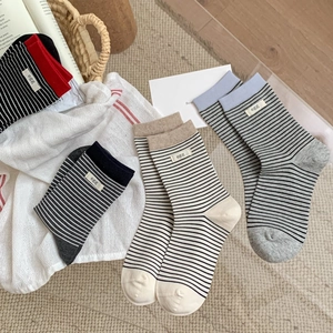 Striped cotton crew socks with 'egg' label shown in a cozy home flat lay arrangement