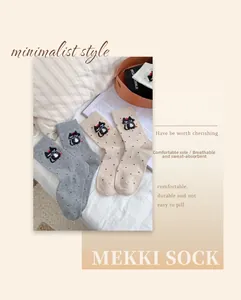 Detailed view of grey and beige cotton crew socks with cute black cat embroidery and polka dots