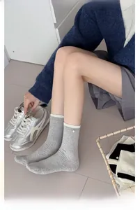 Détail de chaussettes grises en coton côtelé avec perle blanche et ourlet contrasté