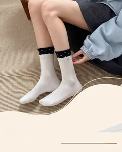 Close-up of white cotton crew socks with black heart pattern trim and ribbed texture