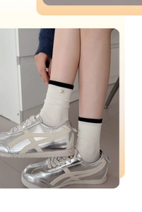 Gros plan de chaussettes mi-mollet en coton crème avec perle et bordure en tricot noir