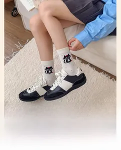Detail view of cream mid-calf socks with black cartoon cat print and ribbed cuffs