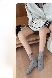 Detail of grey cotton mid-tube socks featuring blue polka dots and a red mushroom patch