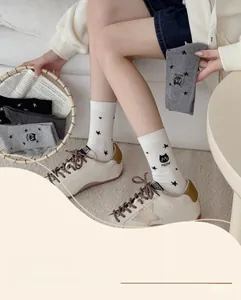 Détail de chaussettes en coton avec motifs d'étoiles noires et chat de dessin animé brodé
