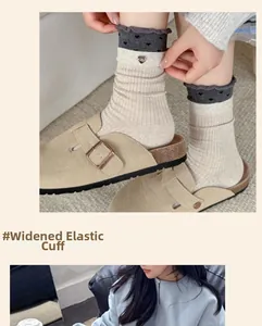 Close-up of wide elastic cuff with wavy edges and heart charm on ribbed knit socks