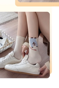 Detail of cream cotton sock with upside-down bear and red ACCELER text in white sneakers