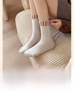 Detail of beige ribbed cotton socks with brown striped cuffs on a cozy corduroy background