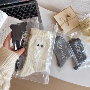 Detail of embroidered eyes on ribbed cotton socks with minimalist gift packaging