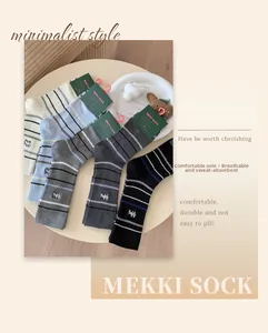 Détail de cinq paires de chaussettes en coton rayées avec broderie sur plateau blanc