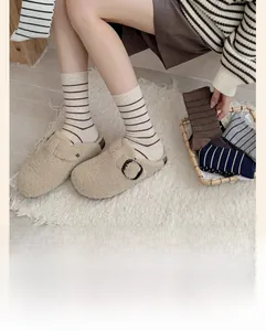 Gros plan de chaussettes rayées en coton peigné portées avec des sabots en peluche