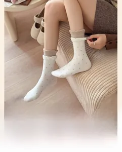 Détail de chaussettes en coton blanc à pois gris avec bordures à volants double couche