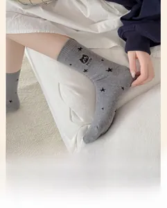Détail de chaussettes grises en coton avec étoiles noires et broderie de chat avec texte MEOW