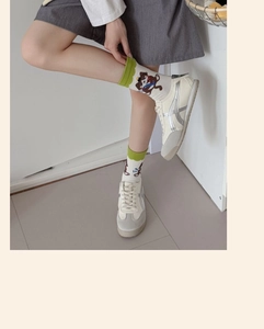 Detail of white crew socks with bear embroidery and wavy cuff paired with retro sneakers