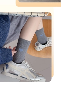 Détail de chaussettes mi-mollet grises côtelées avec broderie petit coeur bleu