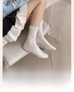 Detailed view of light gray ribbed crew socks with white lace trim on a model