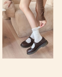 Detail of dark brown Mary Jane shoes paired with retro striped cotton mid-calf socks