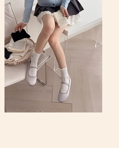 Detail of white hollow ruffle socks paired with grey Mary Jane shoes in a preppy style