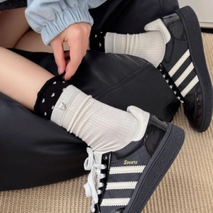 Black synthetic leather sneakers with white stripes and heart-decorated crew socks
