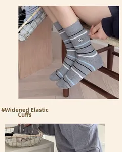 Détail de chaussettes grises rayées en coton avec broderie chien et revers élastique
