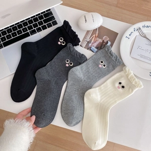 Close-up of cute cartoon eye embroidery and ruffle cuffs on premium cotton socks