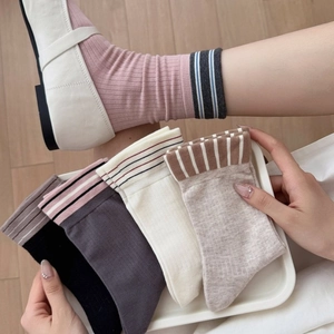 Five pairs of Japanese-style striped crew socks in pastel colors on wooden background