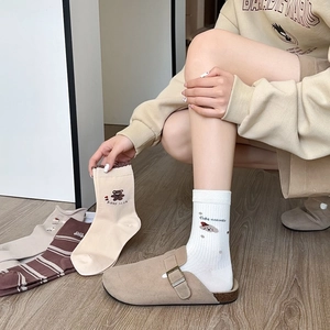 Détail des motifs ours et chien brodés sur des chaussettes en coton marron et beige