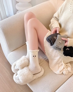 Detail of white ruffle trim crew socks featuring cute cartoon eye embroidery and ribbed texture
