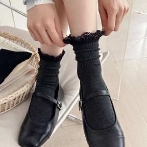 Knit mid-calf socks with delicate lace trim paired with classic black Mary Jane shoes