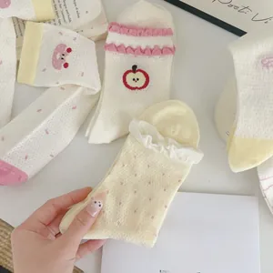 Detail of sweet mesh mid-calf socks with apple embroidery and polka dot patterns