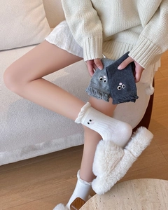 Detail of white and gray mid-calf socks with cute cartoon eyes and wavy lace edges