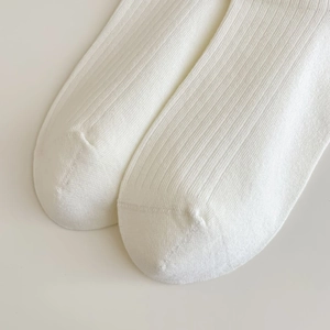 Gros plan de chaussettes en coton blanc côtelé montrant les coutures et la texture