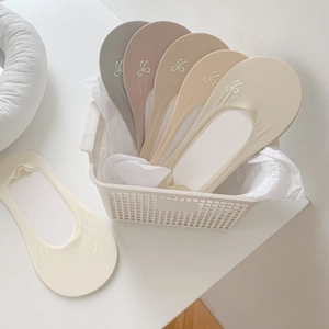 Close-up of five earth-tone low-cut socks with white bow prints in a woven basket