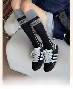Détail de chaussettes hautes de sport noires et grises avec rayures latérales et texte