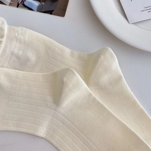 Detailed macro view of the cream white ribbed cotton knit fabric on mid-calf socks