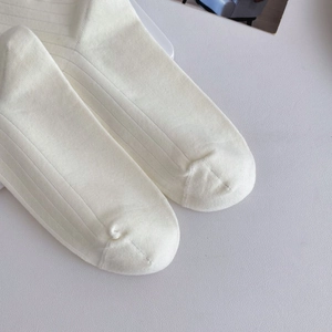 Close-up of white ribbed knit cotton socks showing detailed toe seam and fabric texture